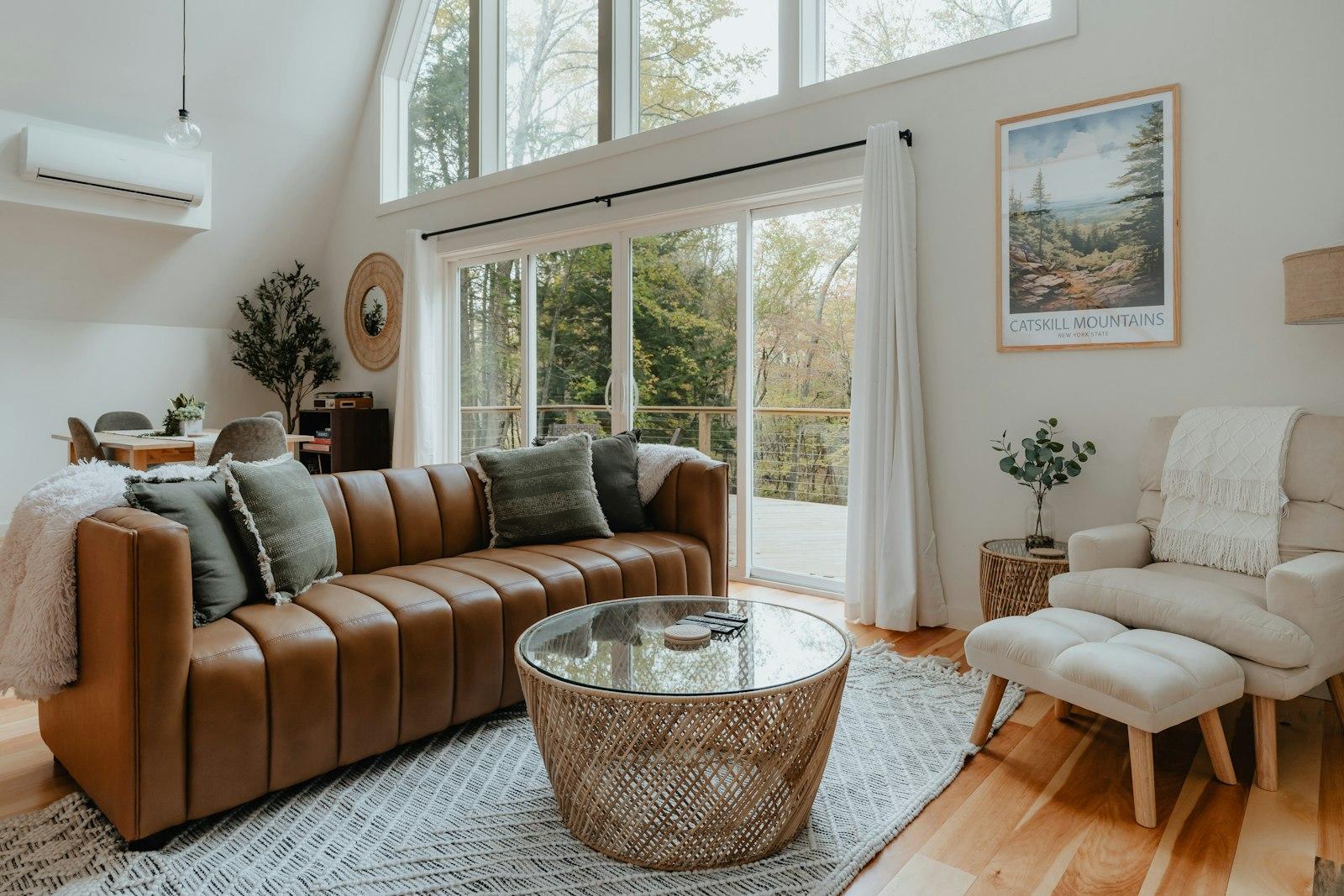 An A-frame cabin living room with a leather sofa and tall windows. Photo by Clay Banks on Unsplash.