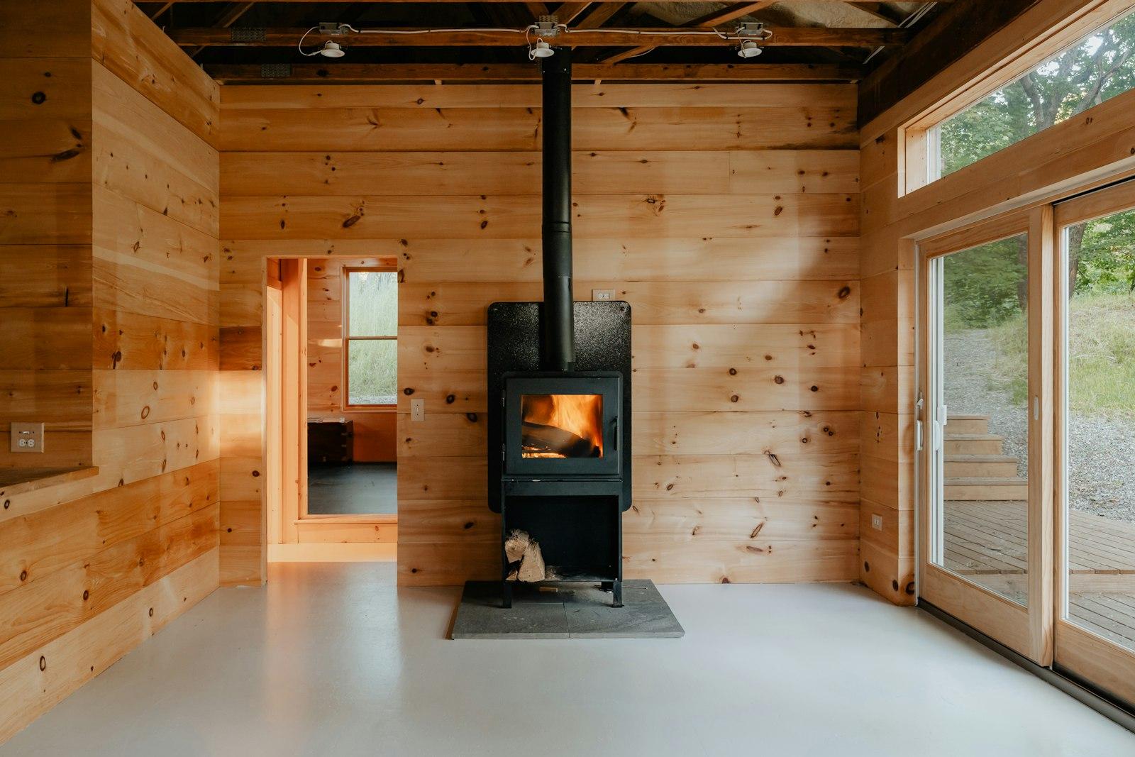 A wood-burning stove glowing inside a cedar cabin. Photo by Clay Banks on Unsplash.